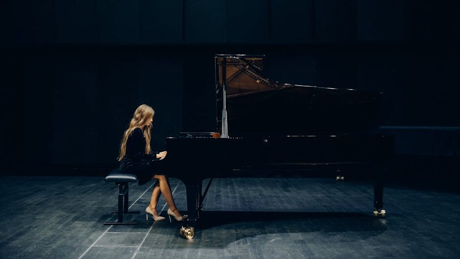 A female pianist elegantly performing on a grand piano in a dimly lit concert hall.