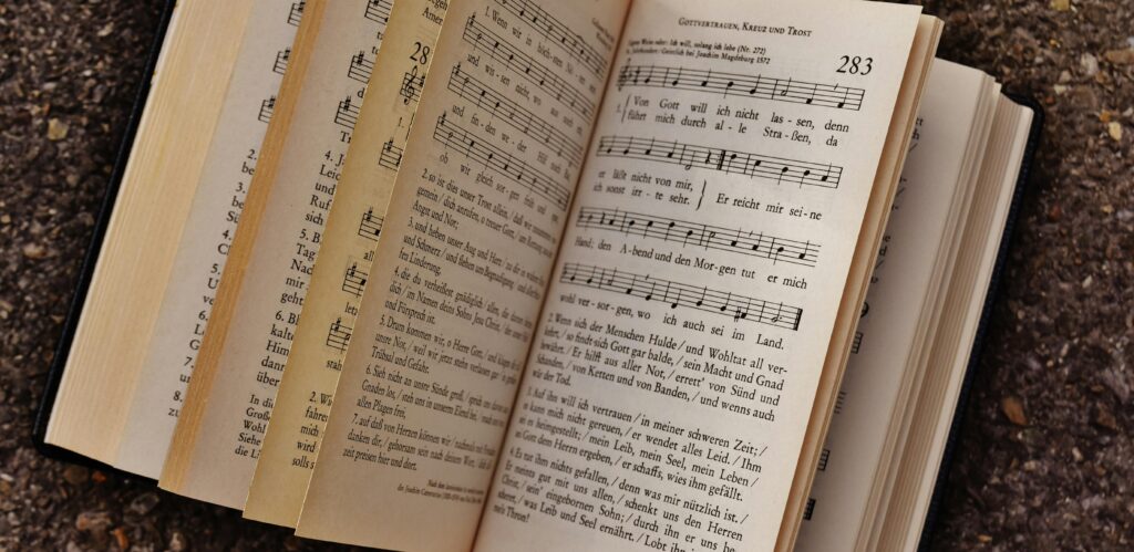 Close-up of an open book displaying musical notes and lyrics on a textured ground surface.