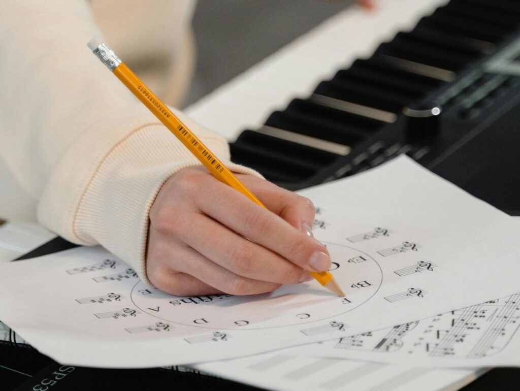 Creating music sheets while playing piano. Perfect for education and creativity themes.