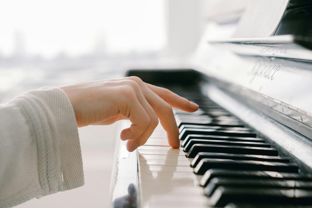 A close-up of a hand gently playing piano keys, capturing the essence of music.