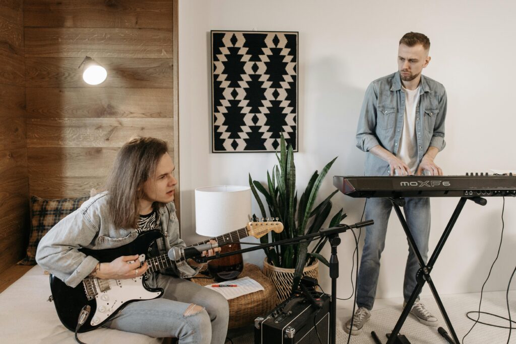 Two musicians playing guitar and keyboard in cozy home setting. Perfect for a relaxed vibe.