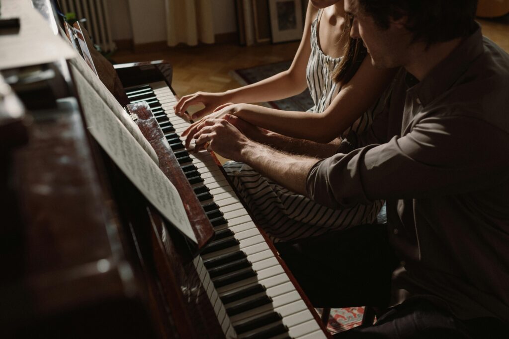 A couple playing piano together, showcasing musical collaboration and intimacy.