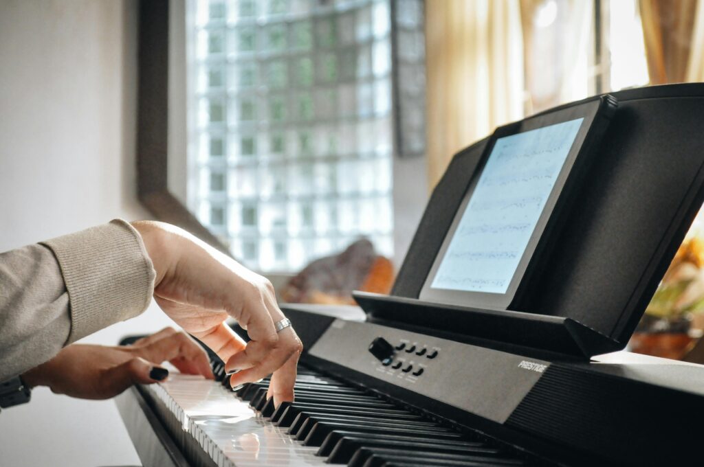 A musician's hands skillfully playing an electric piano indoors, capturing a moment of musical learning.