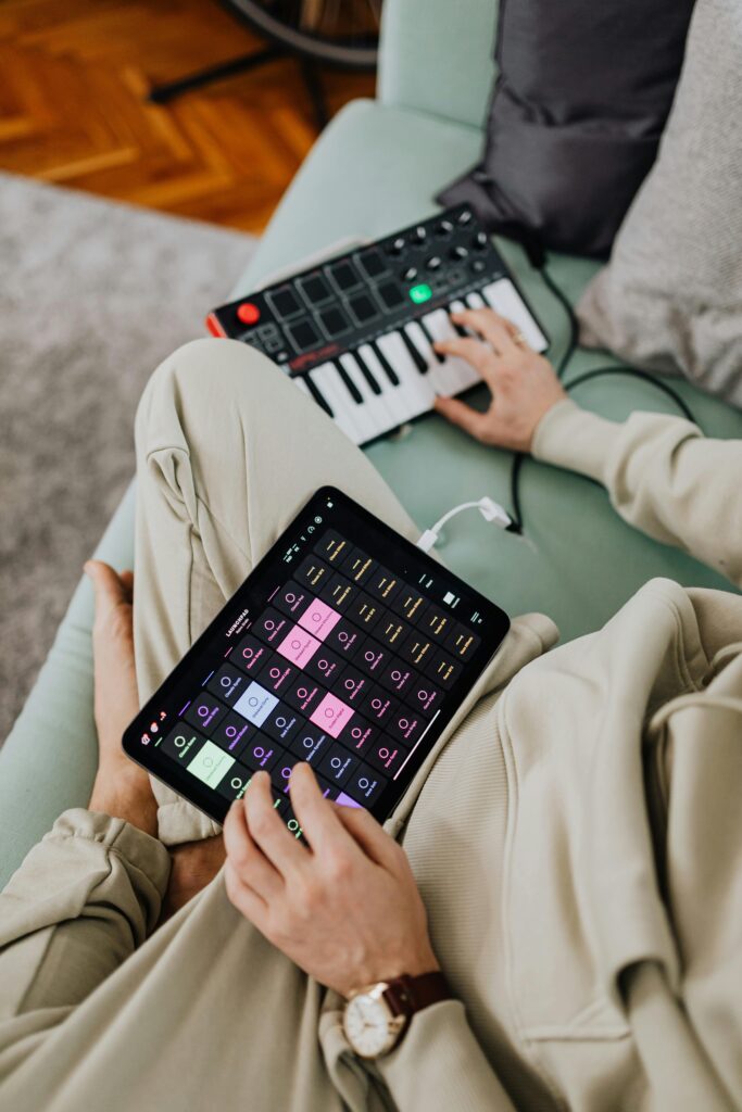 Adult man using a tablet and keyboard to create music at home. Relaxed and casual setting.