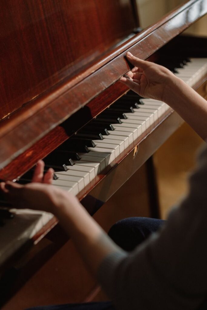 A detailed view of a pianist's hands playing an elegant wooden piano indoors.