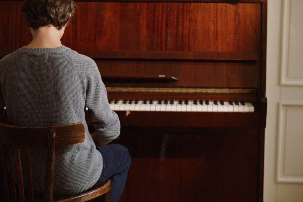 A person sitting and practicing piano indoors, creating a serene musical atmosphere.